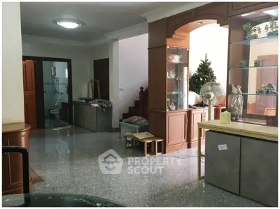 Spacious living area with modern decor and polished flooring, featuring a small Christmas tree and elegant cabinetry.
