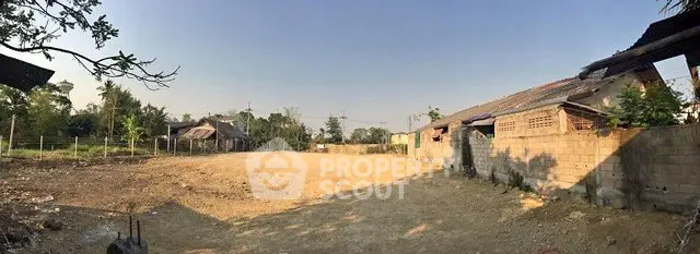 Expansive land plot with rustic buildings, ideal for development in serene countryside setting.
