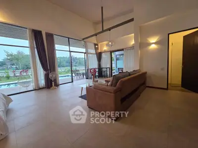 Spacious living room with large windows and garden view, featuring modern furniture and elegant decor.