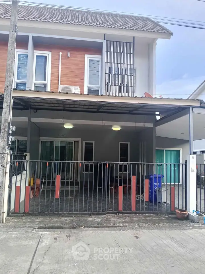 Modern two-story townhouse with gated entrance and covered parking area.