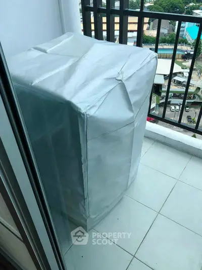 Compact balcony with covered appliance and city view, ideal for urban living.
