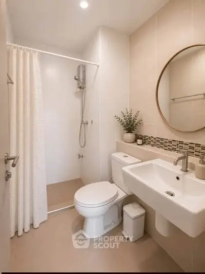 Modern bathroom with shower, toilet, and sink in neutral tones, featuring a round mirror and elegant decor.