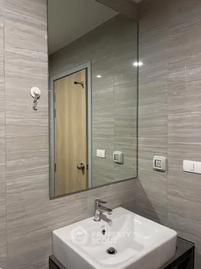 Modern bathroom with sleek sink and large mirror in stylish apartment.