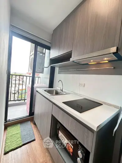 Modern compact kitchen with sleek cabinetry and balcony view, featuring built-in appliances and stylish design.