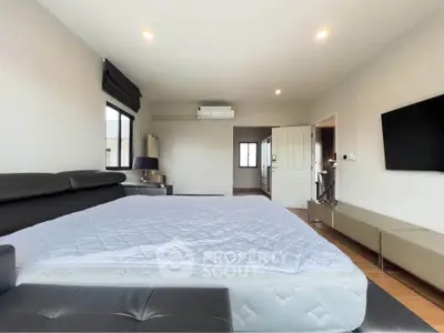 Spacious bedroom with modern furnishings and ample natural light, featuring a large bed and sleek decor.