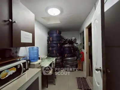 Utility room with stacked tires, microwave, and water dispenser in a residential property.