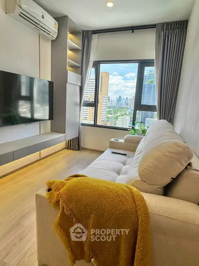 Modern living room with city view, cozy sofa, and sleek TV setup.