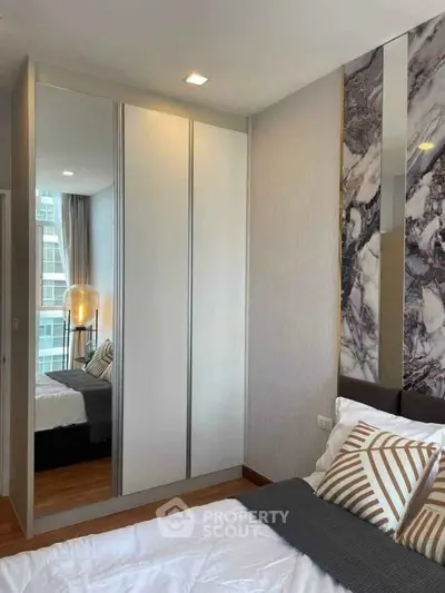 Modern bedroom with stylish decor and mirrored wardrobe in urban apartment.