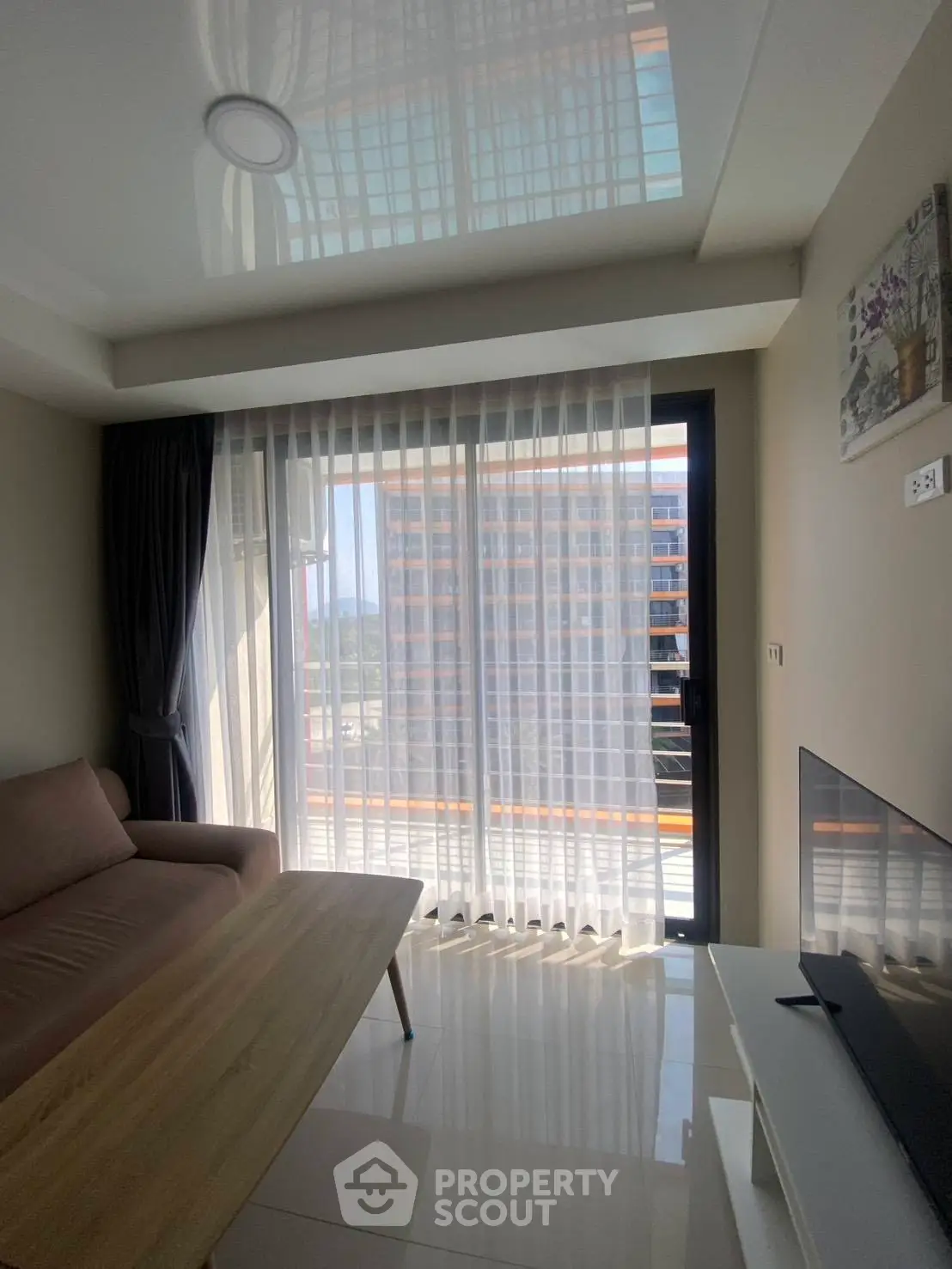 Modern living room with floor-to-ceiling windows and a cozy sofa, offering a bright and inviting atmosphere.