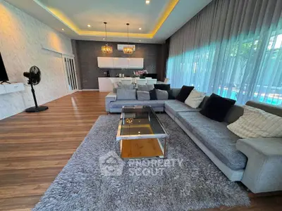 Luxurious modern living room with elegant decor and pool view, featuring a spacious gray sectional sofa and chic lighting.