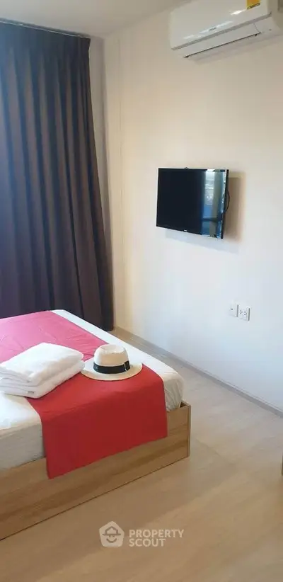 Cozy bedroom with modern decor, featuring a wall-mounted TV and air conditioning for comfort.