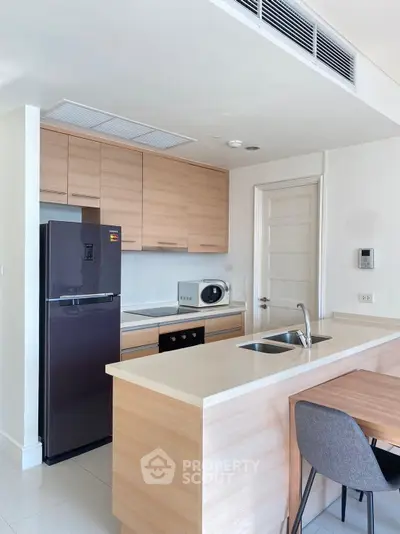 Modern kitchen with sleek wooden cabinets and stainless steel appliances in a stylish apartment.