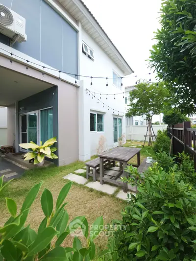 Charming modern home with lush garden and outdoor seating area, perfect for relaxation and entertaining.