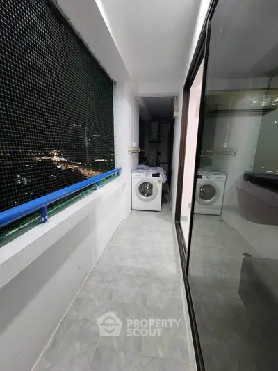 Spacious balcony with city view and washing machine in modern apartment.