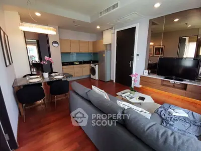 Modern living room with open kitchen, stylish decor, and hardwood floors in a cozy apartment.