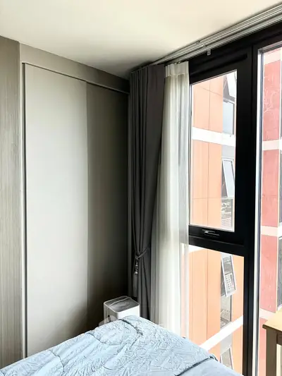 Modern bedroom with large window and stylish curtains in urban apartment