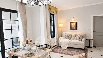 Elegant living room with chic decor and dining area, featuring stylish lighting and cozy seating.