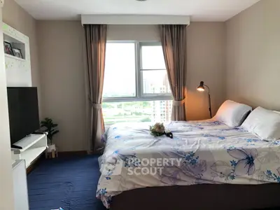 Cozy bedroom with large window and modern decor offering a serene city view.