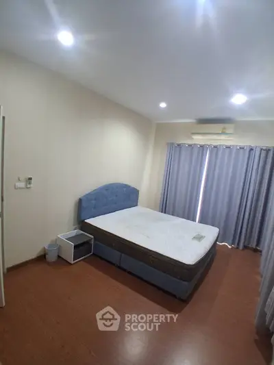 Spacious bedroom with modern design and ample natural light, featuring a comfortable bed and stylish curtains.