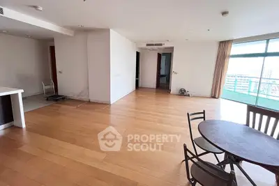 Spacious open-plan living area with wooden flooring and balcony access in modern apartment.