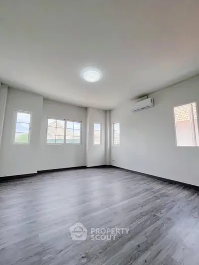 Spacious empty room with large windows and modern flooring, perfect for customization.