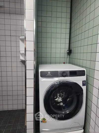 Modern laundry area with a sleek washing machine in a tiled room, perfect for efficient home living.