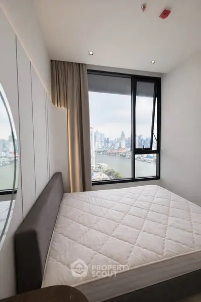 Modern bedroom with stunning city view through large windows, featuring a cozy bed and elegant decor.