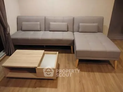 Modern living room with stylish gray sectional sofa and wooden coffee table on hardwood floor.