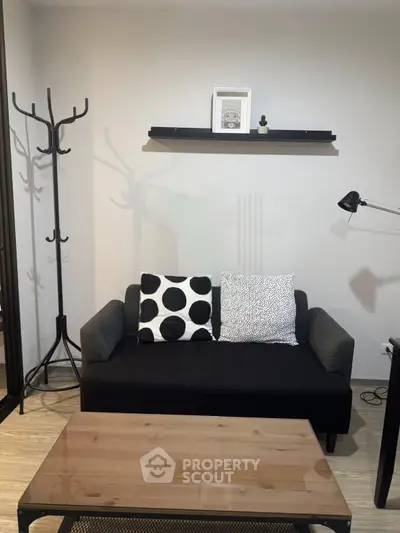 Modern living room with stylish black sofa, decorative pillows, and sleek coffee table.