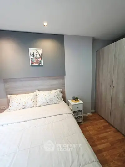 Cozy bedroom with modern decor and wooden flooring, featuring a comfortable bed and stylish wardrobe.