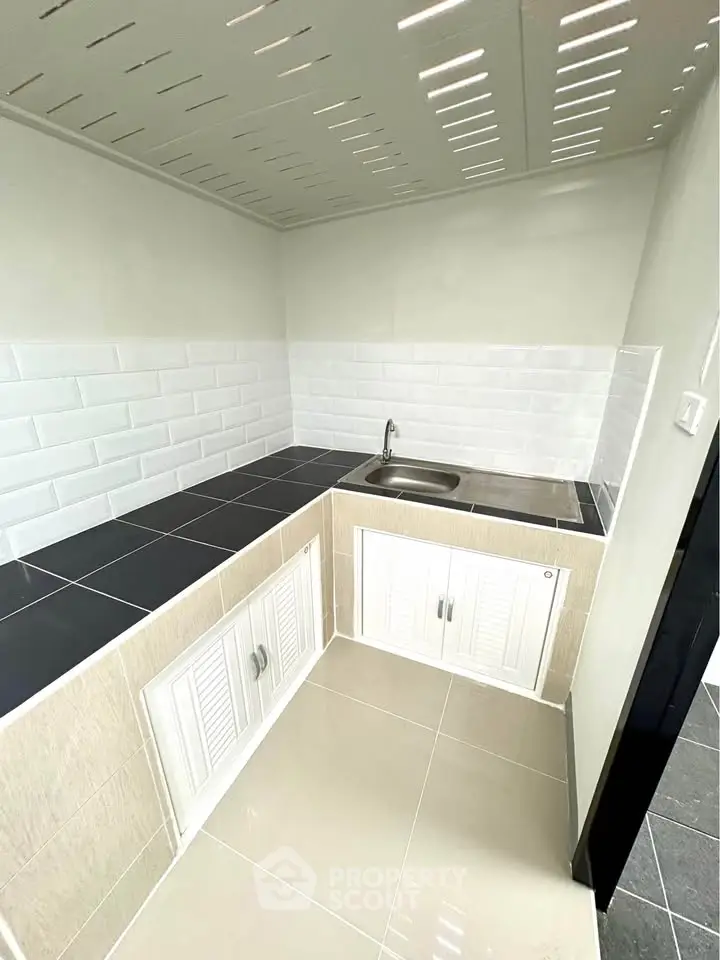 Modern kitchen with sleek black countertops and white cabinets, featuring a minimalist design.