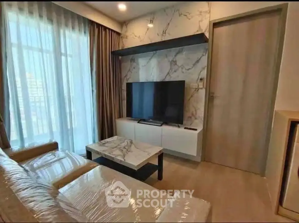 Modern living room with marble accents and large TV, featuring elegant curtains and cozy seating.