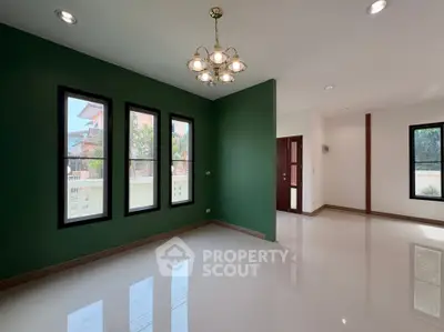 Spacious living room with green accent wall and modern chandelier
