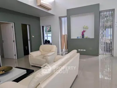 Modern living room with sleek design, featuring white leather sofas and stylish decor.