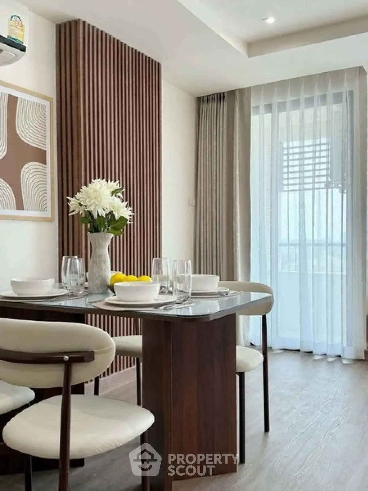 Elegant dining area with modern decor and natural light, featuring a stylish table and chairs near a large window.