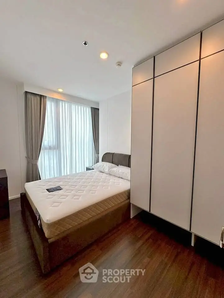 Modern bedroom with large window and stylish wardrobe in a contemporary apartment.