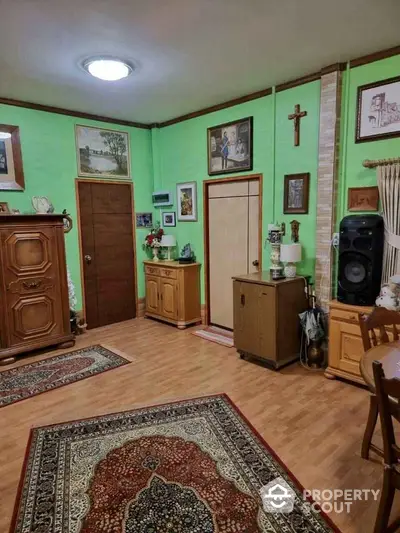 Charming living room with wooden furniture and vibrant green walls, featuring elegant decor and cozy ambiance.