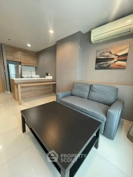 Modern open-layout kitchen and living room with sleek furniture and air conditioning.