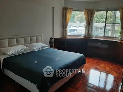 Spacious bedroom with large windows and polished wooden floors, offering a serene and inviting atmosphere.