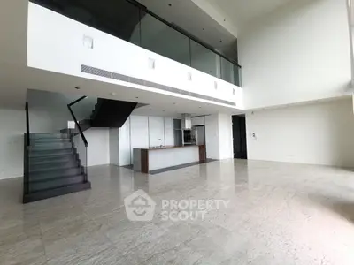 Spacious modern loft with open kitchen and elegant staircase, perfect for contemporary living.