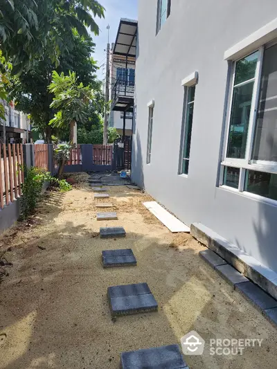 Charming side garden with stepping stones and modern exterior wall