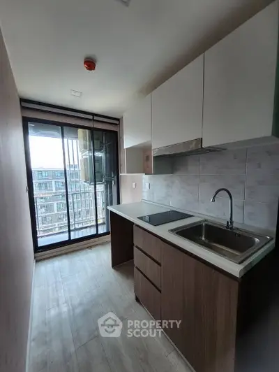 Modern kitchen with sleek cabinetry and large window offering city view