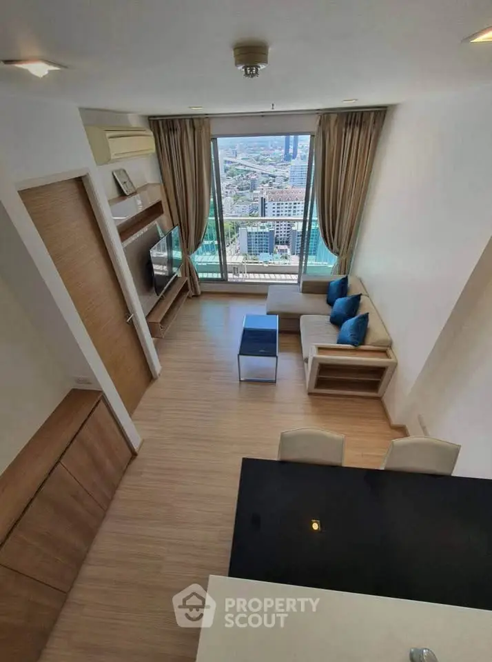 Modern living room with city view, featuring sleek furniture and large windows for natural light.