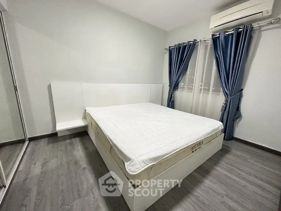 Modern bedroom with sleek design, featuring a comfortable bed, stylish curtains, and air conditioning.