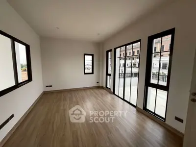 Spacious empty room with large windows and wooden flooring, perfect for customization.