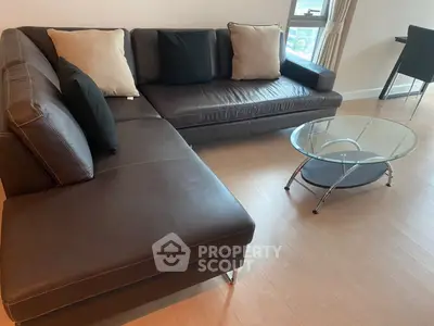 Modern living room with sleek leather sectional sofa and glass coffee table, perfect for stylish urban living.