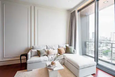 Modern living room with large windows and city view, featuring elegant decor and cozy seating area.