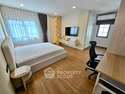 Spacious modern bedroom with wooden flooring and natural light