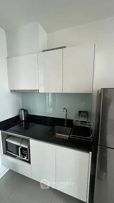 Modern compact kitchen with sleek white cabinets and stainless steel appliances