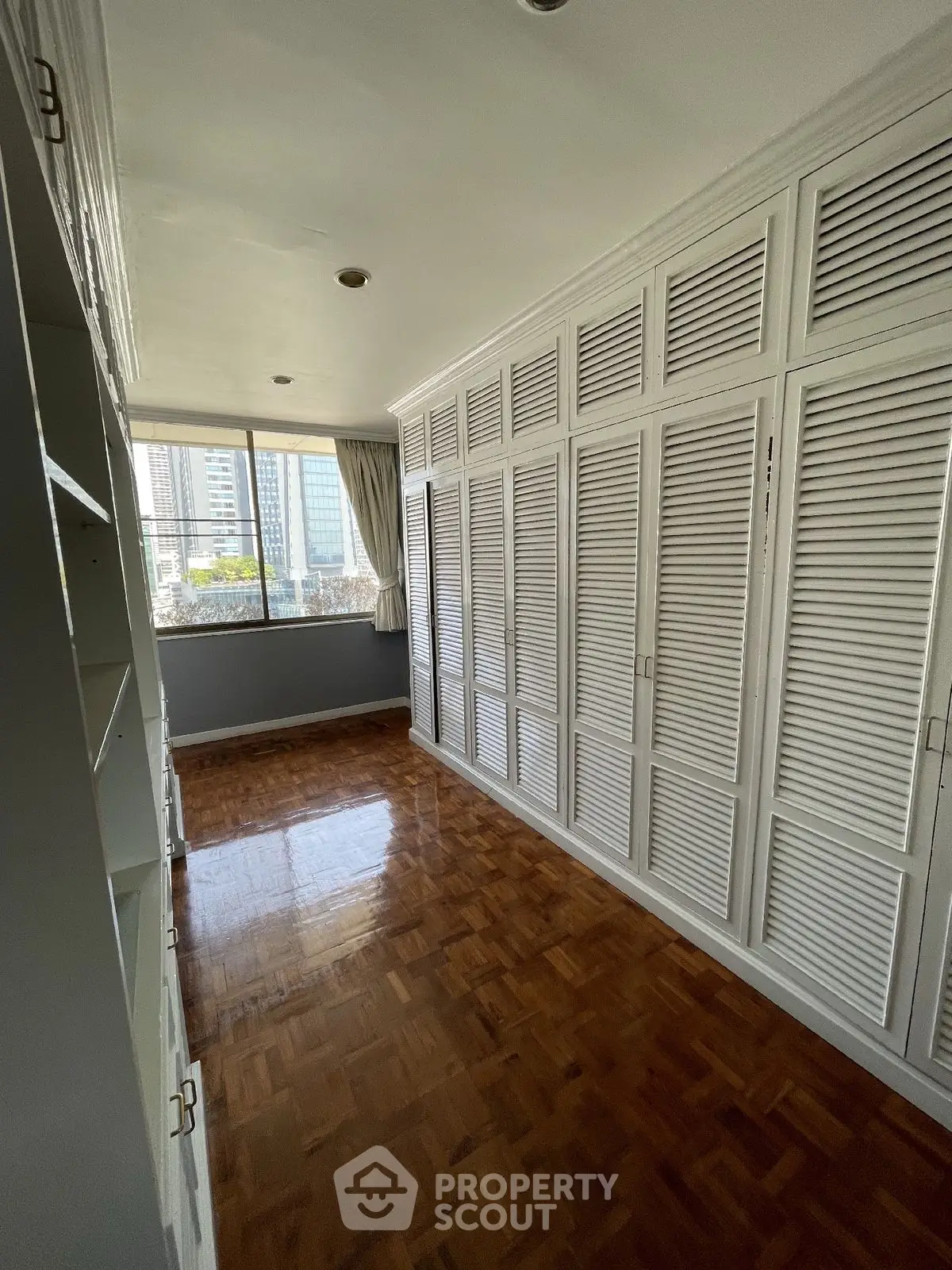 Spacious bedroom with large windows and ample closet space in a modern apartment.